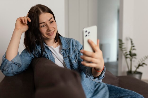 Tiro medio mujer sonriente sosteniendo smartphone