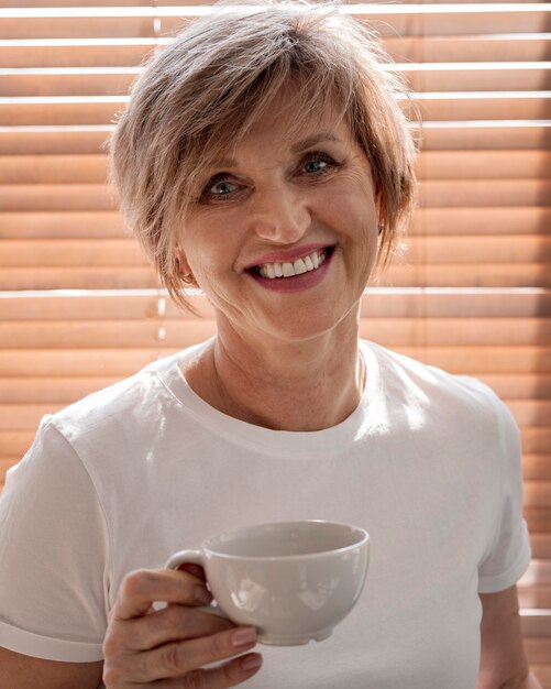 Tiro medio mujer sonriente sosteniendo la taza