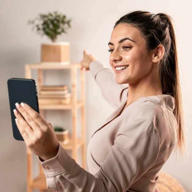 Tiro medio mujer sonriente sosteniendo teléfono