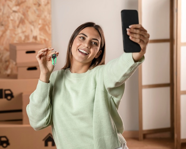 Foto gratuita tiro medio mujer sonriente sosteniendo teléfono