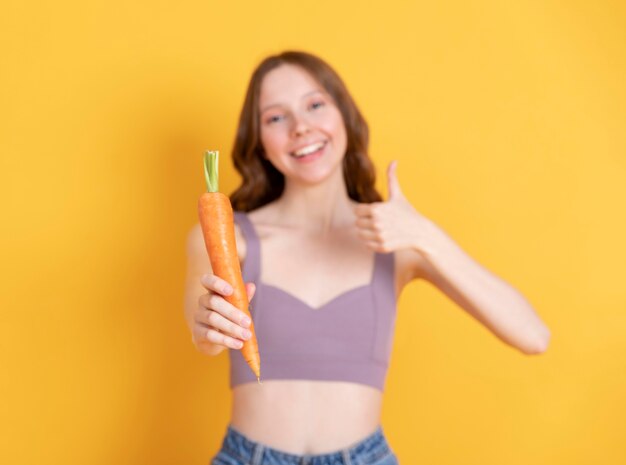 Foto gratuita tiro medio mujer sonriente sosteniendo zanahoria