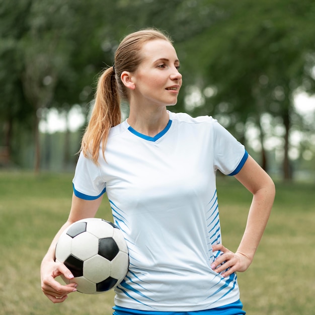 Foto gratuita tiro medio mujer sosteniendo un balón de fútbol