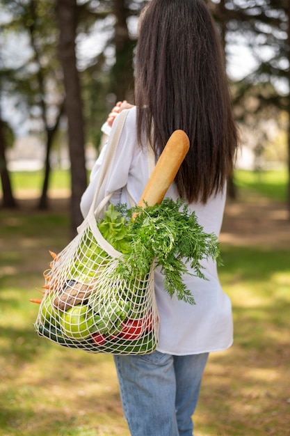 Tiro medio mujer sosteniendo una bolsa reutilizable fuera