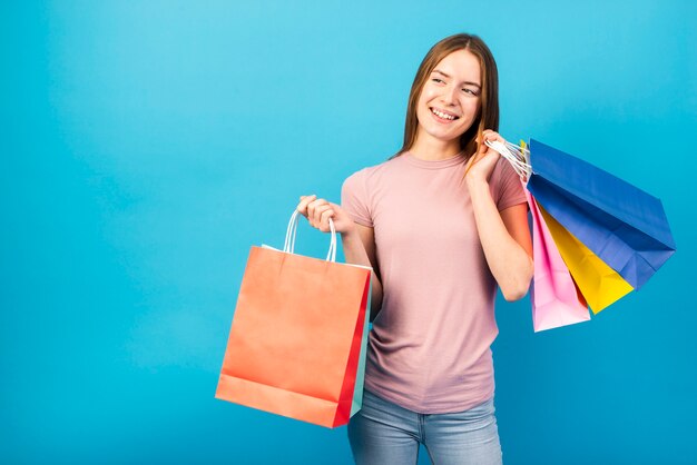 Tiro medio mujer sosteniendo bolsas y mirando a otro lado