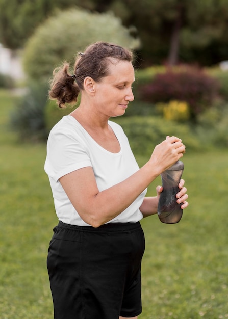 Tiro medio mujer sosteniendo una botella de agua