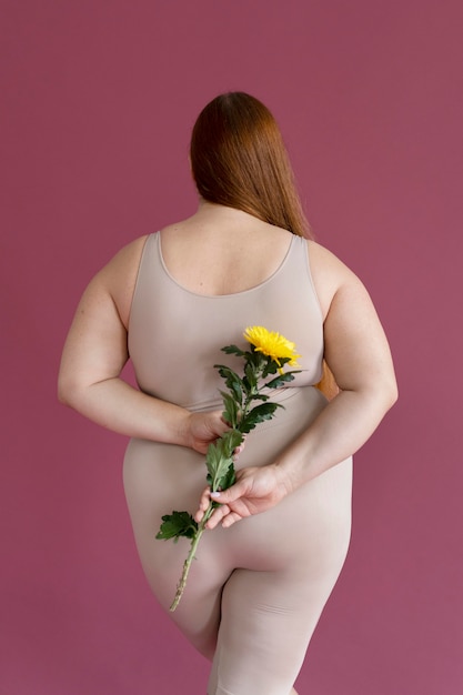 Foto gratuita tiro medio mujer sosteniendo flor vista posterior