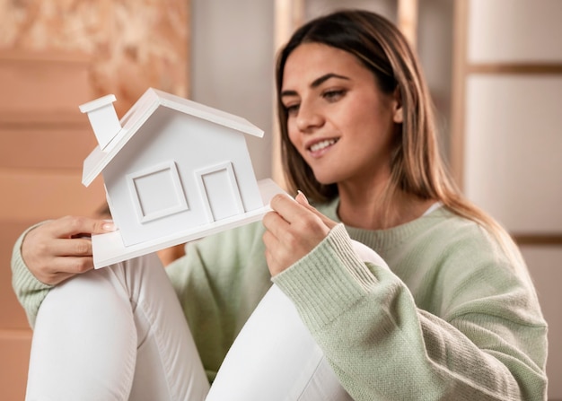 Tiro medio mujer sosteniendo pequeña casa