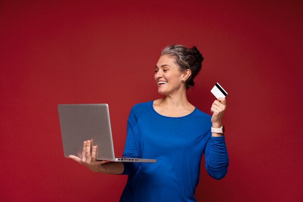 Tiro medio mujer sosteniendo portátil y tarjeta