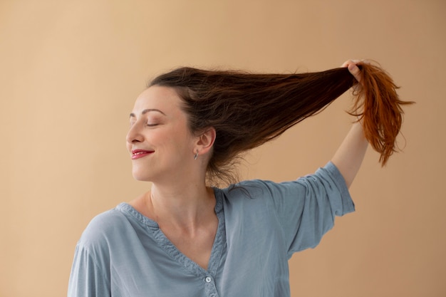 Foto gratuita tiro medio mujer sosteniendo su cabello