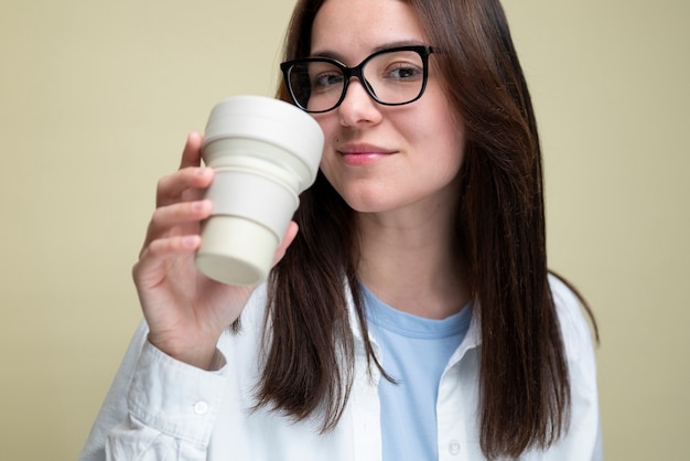 Tiro medio mujer sosteniendo la taza de café