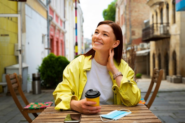 Tiro medio mujer sosteniendo la taza de café