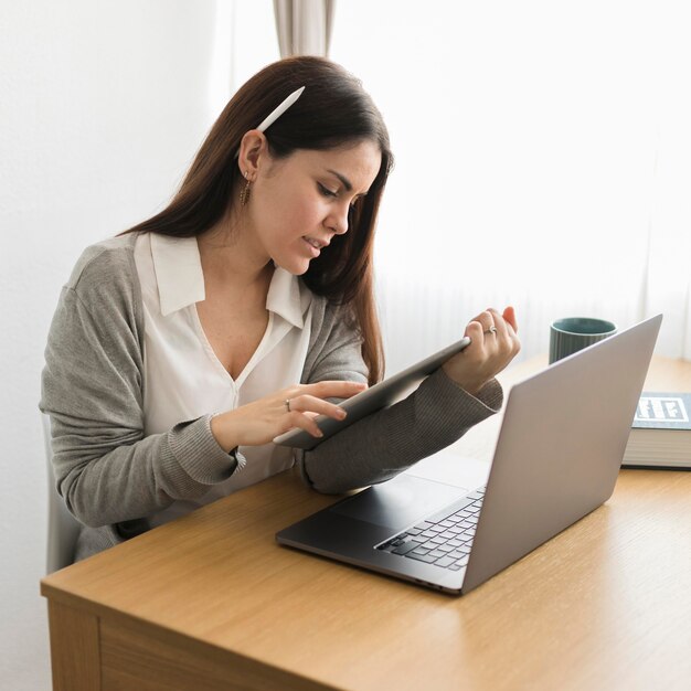 Tiro medio mujer trabajando desde casa en tableta