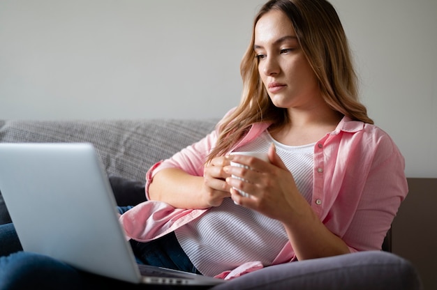 Foto gratuita tiro medio mujer trabajando en el sofá