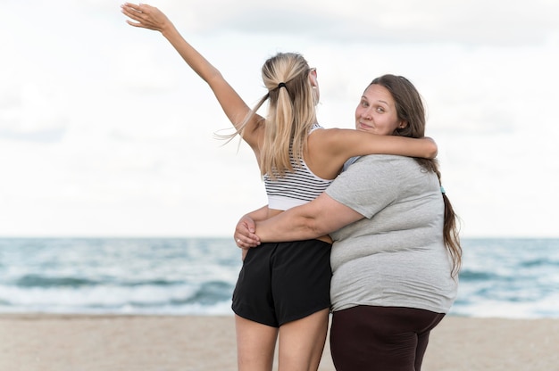 Foto gratuita tiro medio mujeres abrazándose en la playa