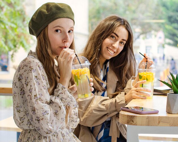 Tiro medio mujeres bebiendo bebidas frescas en la cafetería