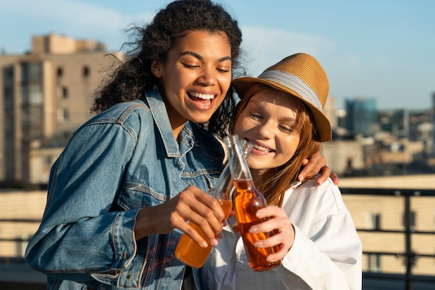 Foto gratuita tiro medio mujeres felices tintineando botellas