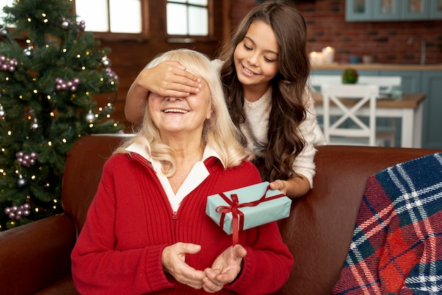 Foto gratuita tiro medio nieta sorprendente abuela con regalo