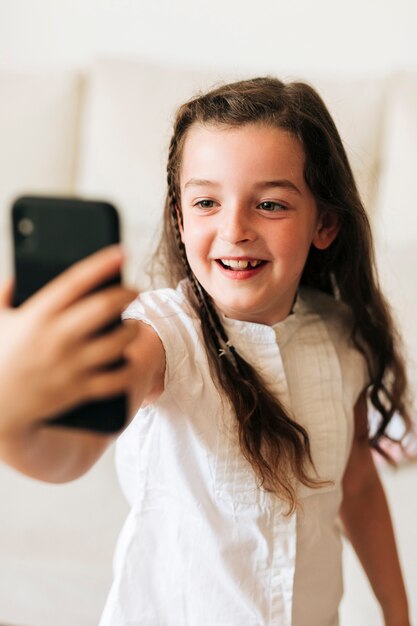Tiro medio niña feliz tomando un selfie