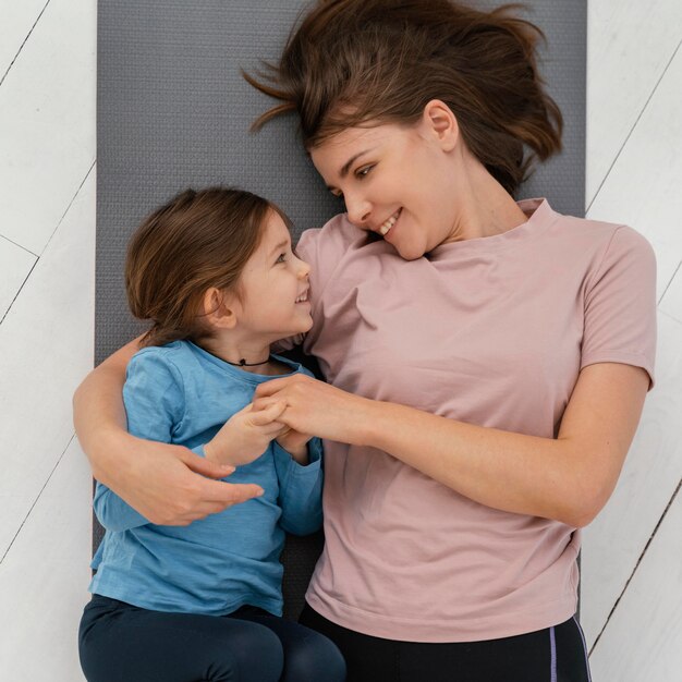 Tiro medio niña y madre en mat