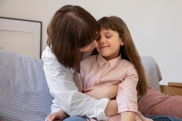 Tiro medio niña y madre en el sofá