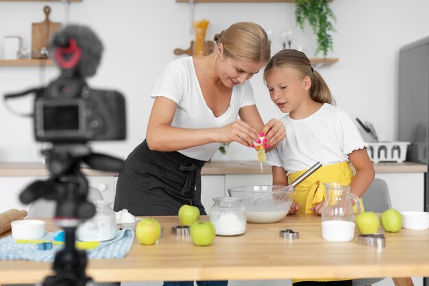 Tiro medio niña y mujer cocinando juntos