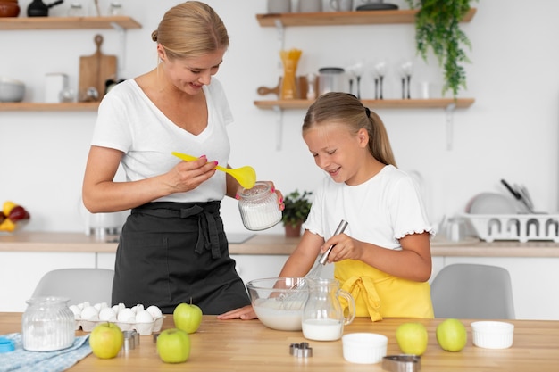 Tiro medio niña y mujer haciendo comida