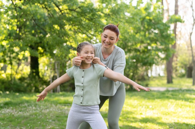 Foto gratuita tiro medio niña y mujer haciendo ejercicio al aire libre