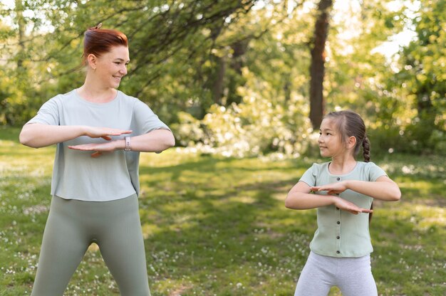 Tiro medio niña y mujer haciendo ejercicio juntos