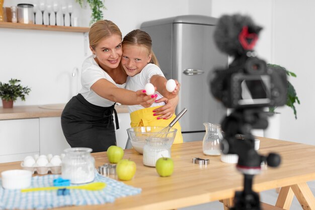 Tiro medio niña y mujer sosteniendo huevos