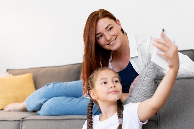 Tiro medio niña y mujer tomando selfie