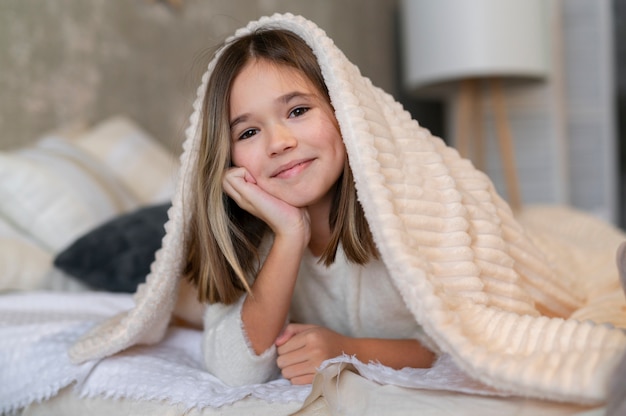 Tiro medio niña sentada en la cama