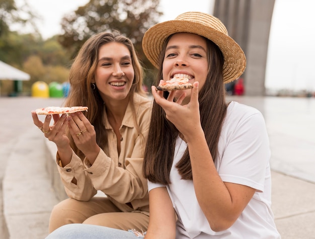 Foto gratuita tiro medio niñas felices comiendo pizza