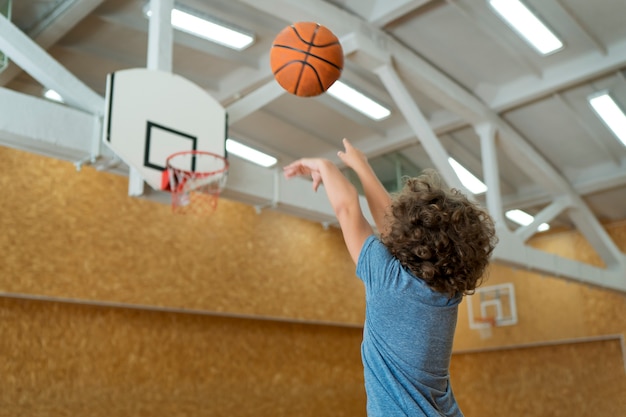 Tiro medio niño lanzando baloncesto