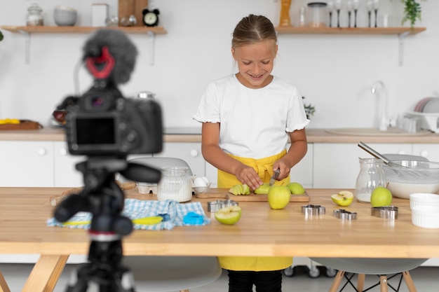 Tiro medio niño sonriente cortando manzanas