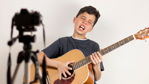 Tiro medio niño tocando la guitarra