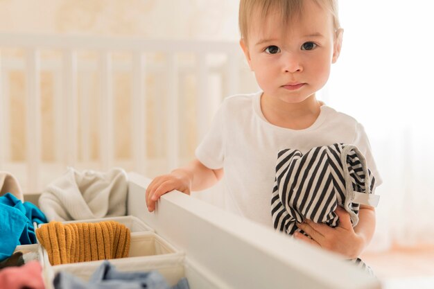 Tiro medio niño tomando ropa del cajón