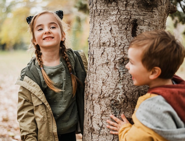 Tiro medio niños felices abrazando el árbol