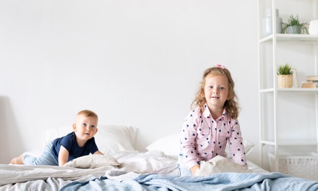 Tiro medio niños felices sentados en la cama