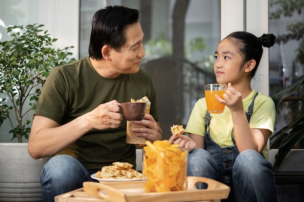 Tiro medio padre y niña tomando un descanso para almorzar