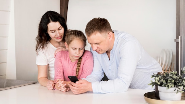 Tiro medio, padres y niña con teléfono