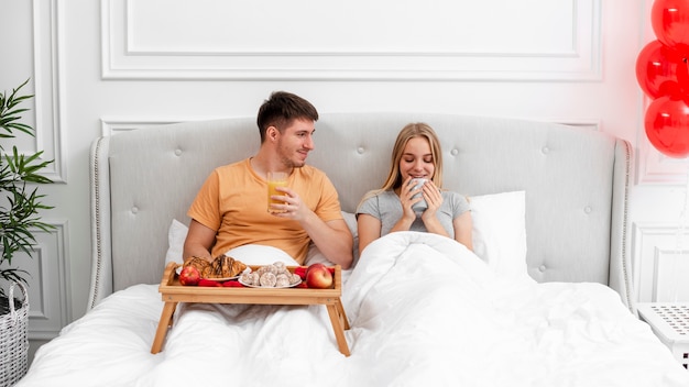 Foto gratuita tiro medio pareja desayunando en la habitación