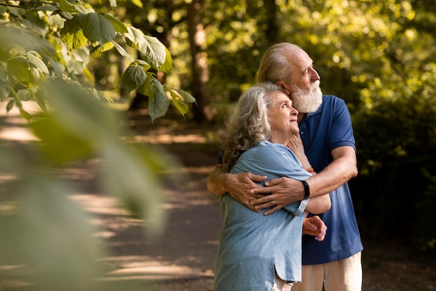 Tiro medio, pareja mayor, abrazar, aire libre