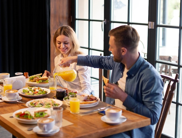 Foto gratuita tiro medio pareja sentada en la mesa