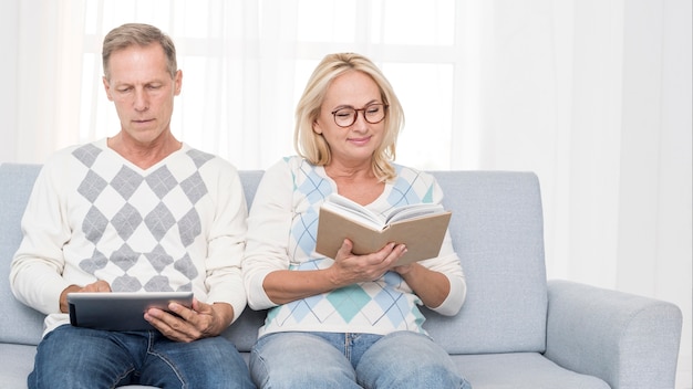 Foto gratuita tiro medio pareja en el sofá leyendo