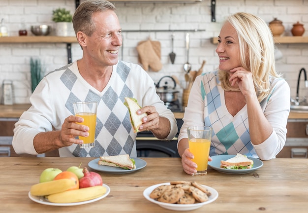 Tiro medio pareja sonriente en la cocina desayunando