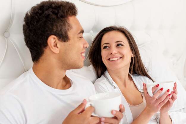 Foto gratuita tiro medio pareja sonriente con tazas de café