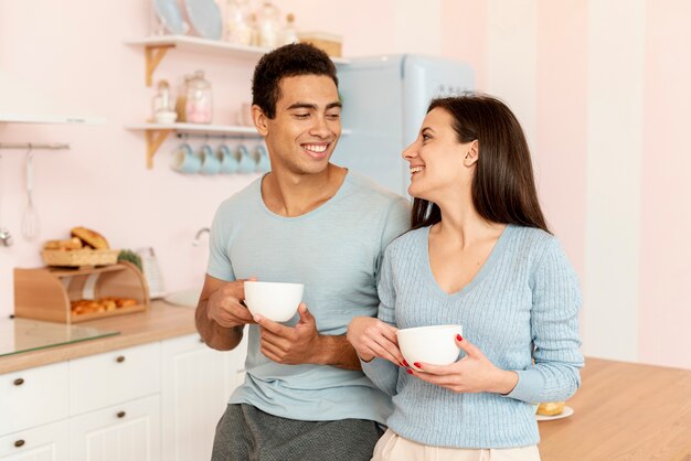 Tiro medio pareja con tazas de café en la cocina