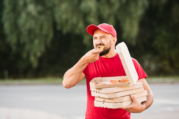 Tiro medio repartidor comiendo pizza