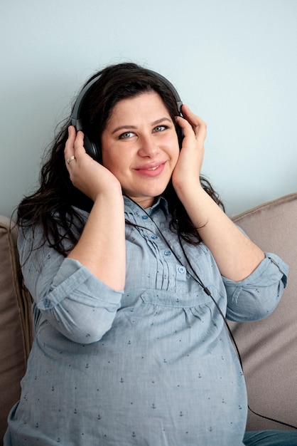 Foto gratuita tiro medio sonriente mujer embarazada con auriculares