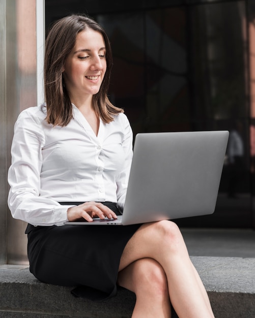 Tiro medio sonriente mujer que trabaja en la computadora portátil